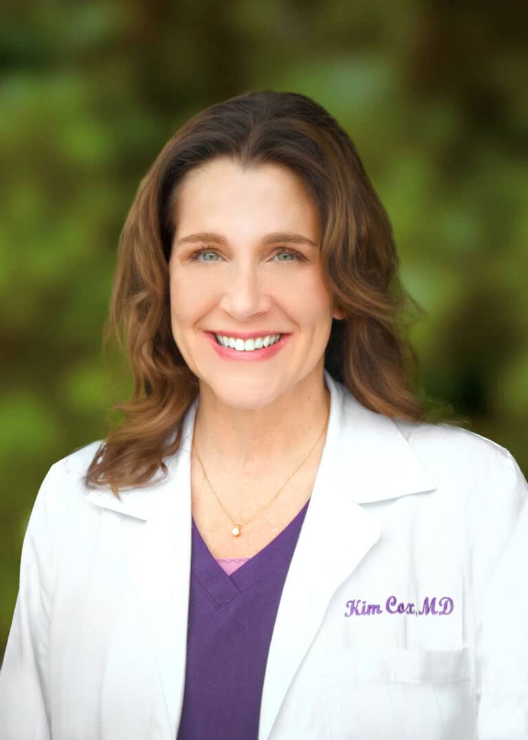 headshot of doctor smiling in lab coat.