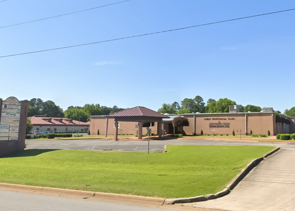 Front-facing view of Athens Professional Plaza with parking lot and awning. Athens Family Health Center is located within this building.